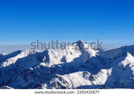 Pointed mountain peaks with deep shadows against the blue sky