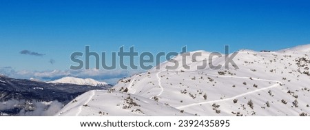 Panoramic view of a snowy hill with traces of skiing