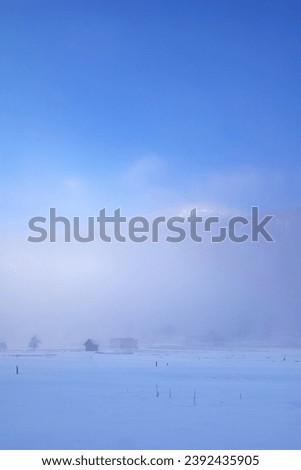 Low fluffy clouds on a snowy field in the foothills of the Alps