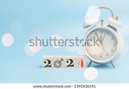 New year 2024 on wood block with vintage a pink alarm clock, copy space blue background. Countdown to new year startup planning financial, budget, set goal challenge for success to the future. Royalty-Free Stock Photo #2392436141