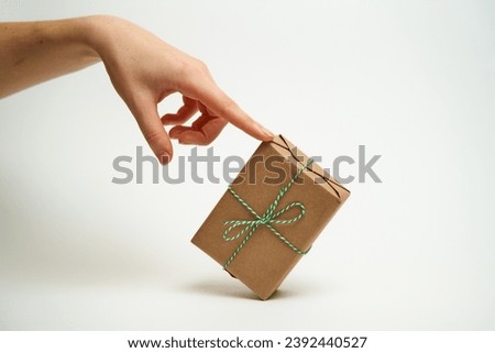 A woman's hand holds a wrapped New Year's gift. Isolated hand on white background. Concept of gifts and New Year holidays.