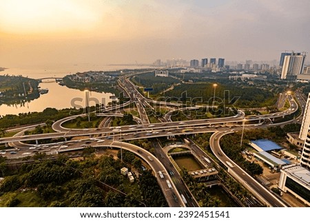 Embrace the dynamic urban landscape with this striking image featuring a prominent flyover or overpass. The elevated roadway creates a striking architectural silhouette against the cityscape Royalty-Free Stock Photo #2392451541