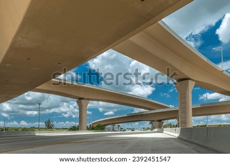Embrace the dynamic urban landscape with this striking image featuring a prominent flyover or overpass. The elevated roadway creates a striking architectural silhouette against the cityscape Royalty-Free Stock Photo #2392451547