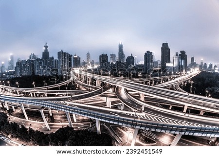 Embrace the dynamic urban landscape with this striking image featuring a prominent flyover or overpass. The elevated roadway creates a striking architectural silhouette against the cityscape Royalty-Free Stock Photo #2392451549