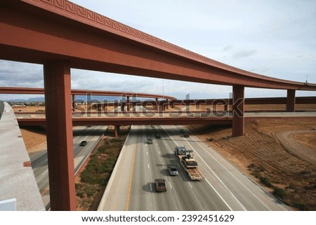 Embrace the dynamic urban landscape with this striking image featuring a prominent flyover or overpass. The elevated roadway creates a striking architectural silhouette against the cityscape Royalty-Free Stock Photo #2392451629