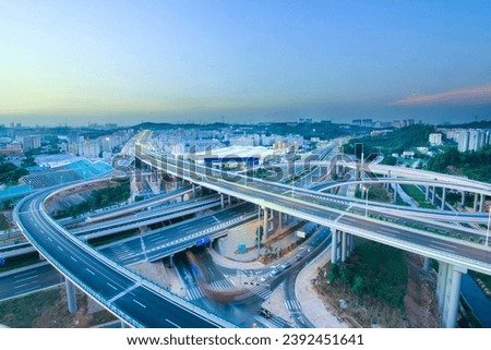 Embrace the dynamic urban landscape with this striking image featuring a prominent flyover or overpass. The elevated roadway creates a striking architectural silhouette against the cityscape Royalty-Free Stock Photo #2392451641