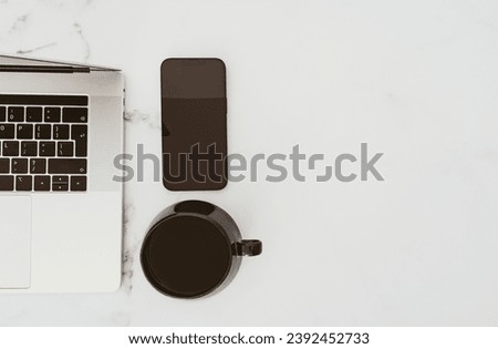 Minimal white office desk table with laptop computer, smartphone with black screen and cup of coffee. Top view. Copy space, flat lay.