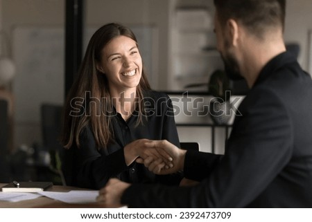 Happy pretty you business professional woman shaking hands with male colleague, smiling, laughing, enjoying teamwork, cooperation. Project managers, business partners giving handshake