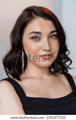 Portrait of a young beautiful girl in a black dress on a gray background