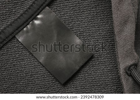Blank black laundry care clothes label on black fabric texture background