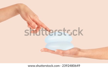 Female hand pointing on breast implants, mammoplasty. Copy space Royalty-Free Stock Photo #2392480649