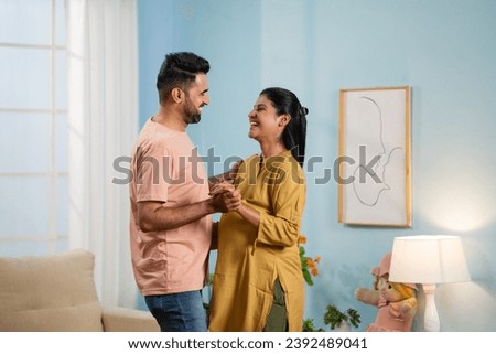 Joyful Indian Pregnant wife with Husband doing romantic dance at home - concept of affectionate, caring husband and affectionate