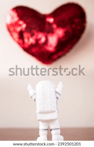 Astronaut pointing up to big red heart on white background