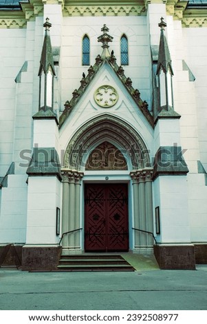 Abstract photograph of the church from the front view. Beautifully decorated church, white facade. gothic door. A built in the Gothic style. Believer, Church, God, Catholic Church.