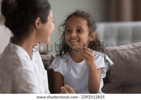 Cute stuttering Indian little girl engaged in class take part in pronunciation lesson with female speech therapist or caring mother, train articulation, repeat words correctly. Kid development concept Royalty-Free Stock Photo #2392512835