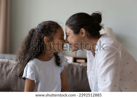 Indian mom and little daughter touch noses enjoy moment of tenderness, express attachment, feel love, valued priceless time together, good friendly relations between mother and child. Family concept Royalty-Free Stock Photo #2392512885