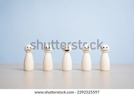 A happy smiling wooden figure stands in the center among many state emotion figures. Individuality, Unique person. Think positive, Pleasure, Feedback rating, Service review. World Mental Health Day Royalty-Free Stock Photo #2392525597