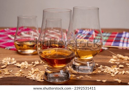 Tasting of different Scotch whiskies strong alcoholic drinks, drum glass of whiskey and colorful Scotch tartan on background close up Royalty-Free Stock Photo #2392531411