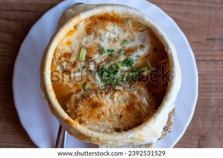 French cuisine, onion soup with melted gruyere cheese and slices of baguette served hot from oven close up