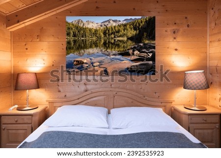 A cosy bed in a hotel room decorated with wooden materials and a picturesque wall photo