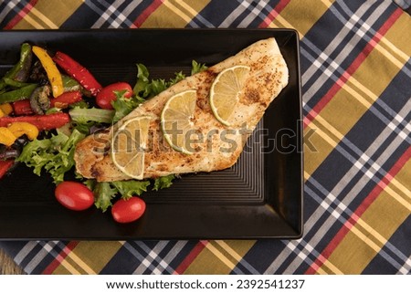 Pand seared fish with salad and sliced lemon garnish
