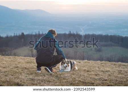 Young cynologist, a dog trainer trains a four-legged pet Australian Shepherd in basic commands using treats. Love between dog and human. Royalty-Free Stock Photo #2392543599