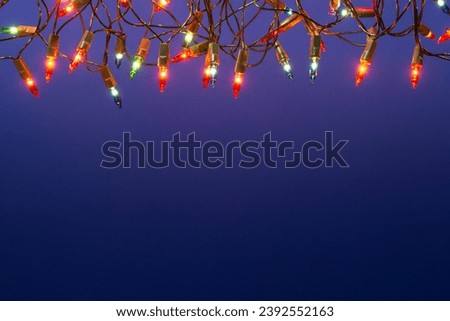 Christmas lights string on blue background with copy space