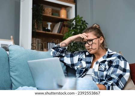 Confused young woman looking on laptop at home feeling bewildered by no connection, reading online news in internet, annoyed teen girl angry with stuck computer problem, scam spam email, system error Royalty-Free Stock Photo #2392553867