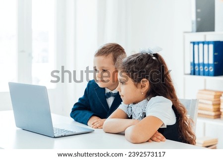 Boy and girl sitting at desk with laptop