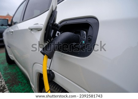 A closeup shot of a white car refueling gasoline by auto dispenser nozzle at a petrol station.