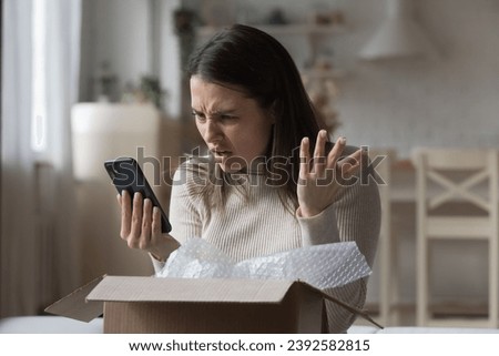 Dissatisfied woman, internet store client got damaged items, receive wrong parcel, make claim send negative feedback use cellphone feels angry. E-commerce mobile app, bad e-shopping experience concept Royalty-Free Stock Photo #2392582815