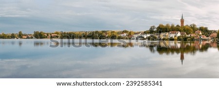 Panoramic view from the northwest over autumnal lake "Haussee" and the skyline of Feldberg with the steeple of its municipal church - panorama from 16 pictures - inscriptions were removed