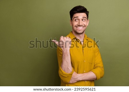 Portrait of nice positive man beaming smile look indicate thumb finger empty space isolated on khaki color background
