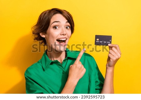 Photo of excited funky lady wear green shirt showing finger bank card isolated yellow color background