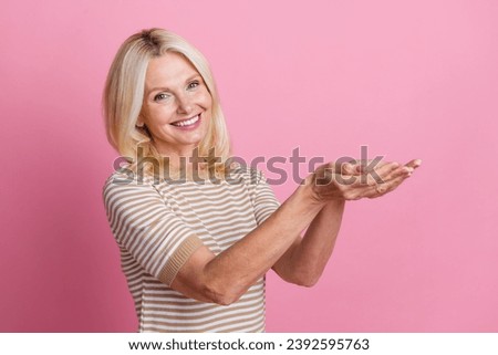 Photo of satisfied person with blond hair dressed striped t-shirt palms demonstrate empty space object isolated on pink color background