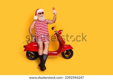 Full length photo of funky senior guy christmas swimwear hat recording video delivering gifts empty space isolated yellow color background