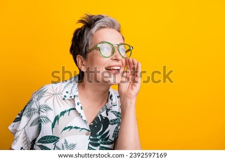 Photo portrait of attractive senior woman share secret cover mouth wear trendy tropical print clothes isolated on yellow color background
