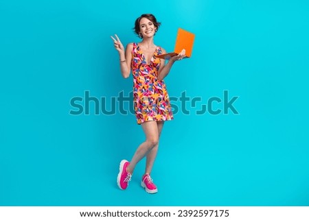 Full length photo of shiny pretty lady wear print clothes showing v-sign chatting modern device isolated blue color background