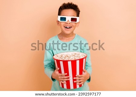 Portrait of cheerful nice schoolchild hands hold big popcorn bucket watch movie 3d glasses isolated on beige color background