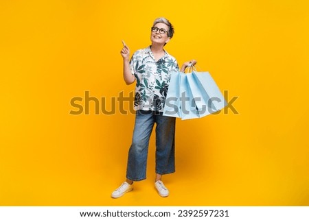 Full body photo of nice pensioner lady shopper point look empty space wear trendy tropical print outfit isolated on yellow color background