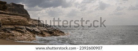 The beach of Nazare in portugal with lighthouse on the mountain with not wavy sea Royalty-Free Stock Photo #2392600907