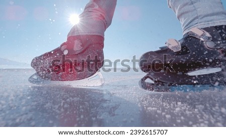 LENS FLARE, CLOSE UP: Male ice skater stops in front of camera on a frozen pond