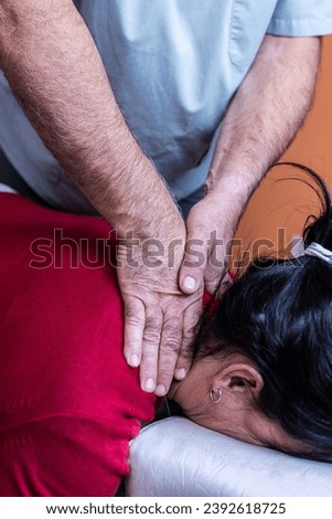 Focused vertical photo of a man's hands massaging his patient's back. Cervicodorsal adjustment with drop