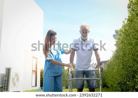 Female nurse or doctor help elderly patient lean to walk with orthopedic walker at outside, patient practice walking in garden with physiotherapist, nursing senior people at home, medical health care.