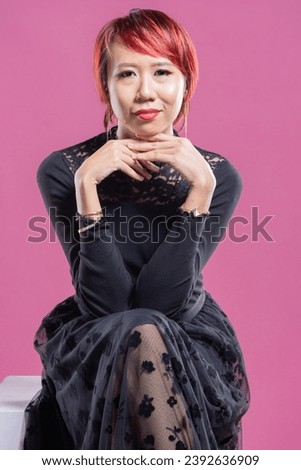 Asian women with red hair over studio background with black dress.