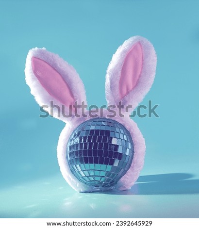 Easter Rave: A Blue Nightclub Disco Ball Wearing Pink Rabbit Ears on a Pastel Blue Background, Nightlife, DJ Club Concept Royalty-Free Stock Photo #2392645929