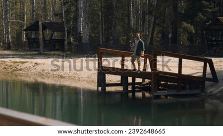 Man with dog on pier. Stock footage. Man picks up dog and walks to edge of pier on lake. Man walks with dog on beautiful lake on sunny summer day
