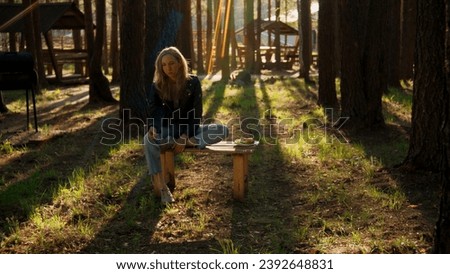 Beautiful blonde woman near wooden pavilions in the summer forest. Stock footage. Woman enjoying nature alone.