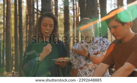 Friends communicate and eat food from barbecue in nature in summer. Stock footage. Friends are having fun talking and eating in woods on sunny summer day. Bright cheerful communication of friends in