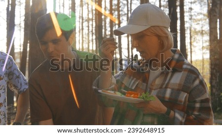 Friends eat delicious fresh food in nature. Stock footage. Friends have fun relaxing in nature and eat delicious food on grill. Friends eat from grill on background of sunlight in summer forest